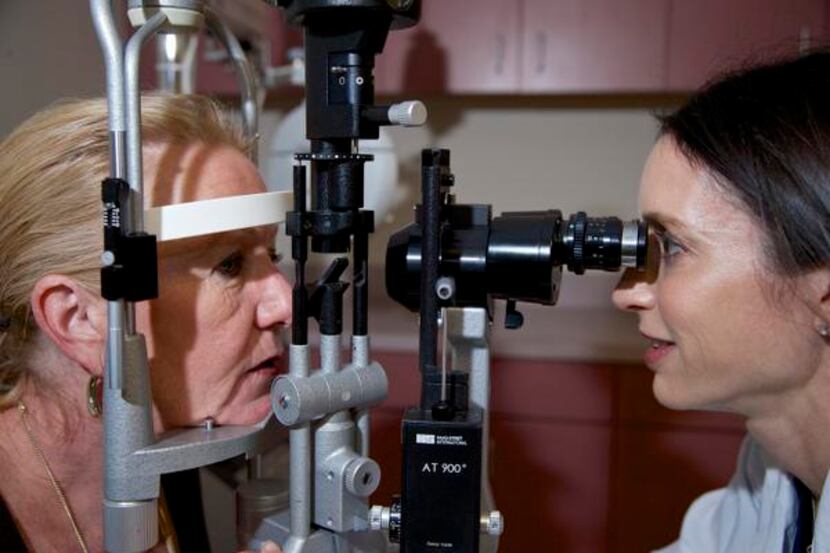 
Ophthalmologist Dr. Karen Saland (right) demonstrates how she inspects patients’ eyes with...