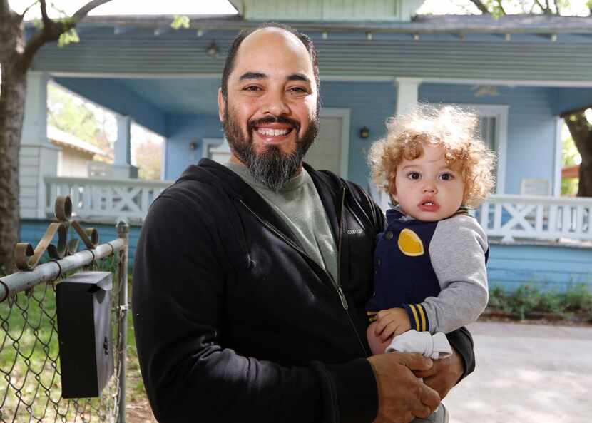 Jesse Gonzalez stands with his son, Tobias Gonzalez, 17 months, in front of one of several...