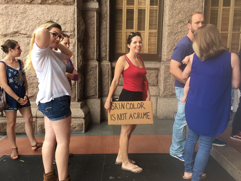 Bianco Arvin of Austin carries a sign into the Texas Capitol amid a protest against the...