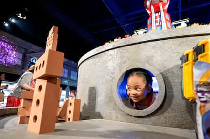 Ariana Brown, 7, peers out of a hole at 'The Paw Patrol Experience' in Dallas.