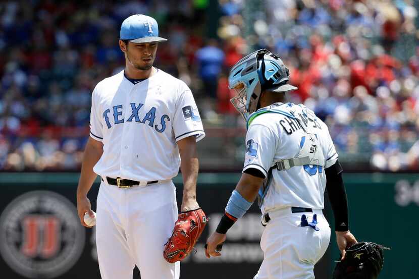 Texas Rangers' Yu Darvish, left, of Japan, talks with catcher Robinson Chirinos, right,...