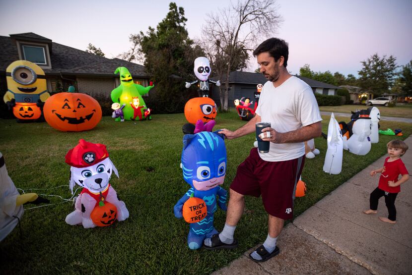 Jason Regas and his son Weston Regas, 3, adjust inflatables as they rise from the lawn...