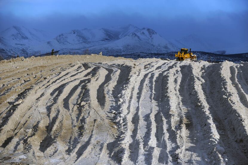 Heavy equipment pushes snow at an Alaska snow dump site in Anchorage.