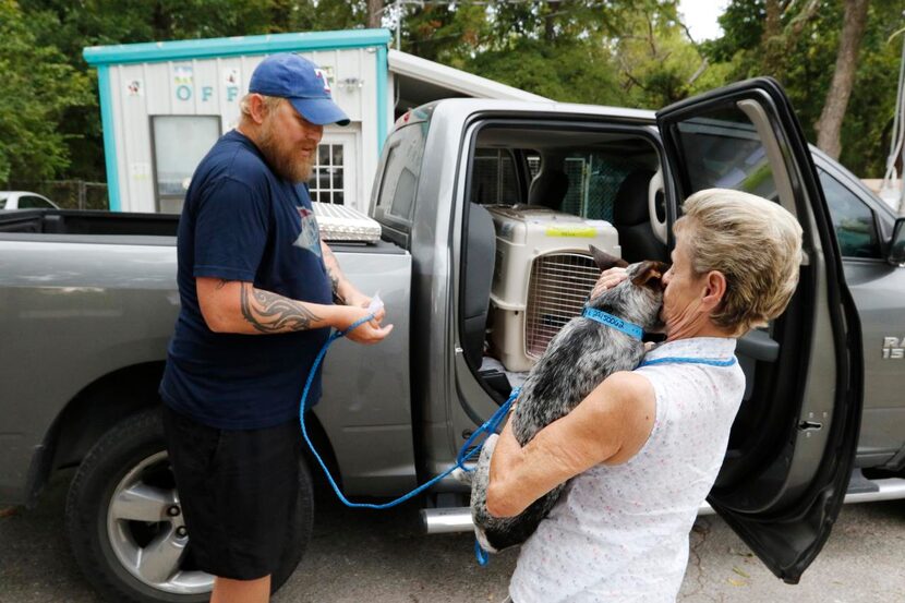 
Carol Merritt (right) hugs one of her rescue dogs before saying good-bye and handing it off...