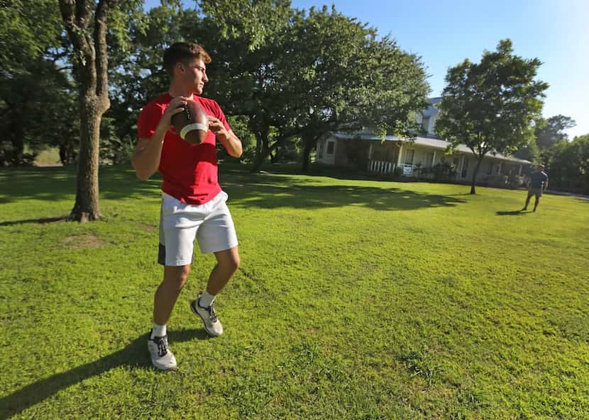 High school quarterback Ken Seals plays catch with his father Robert Seals at their home in...