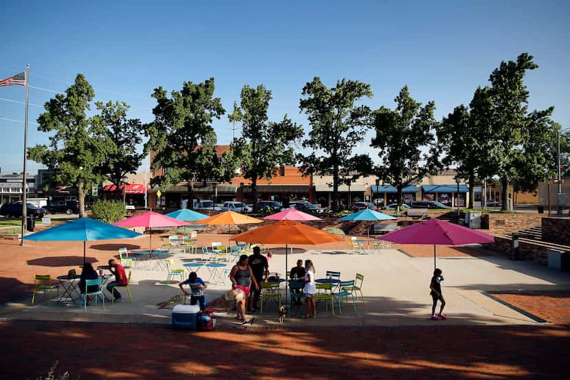People find shade from the sun in Garland City Square in downtown Garland, Texas, Friday,...
