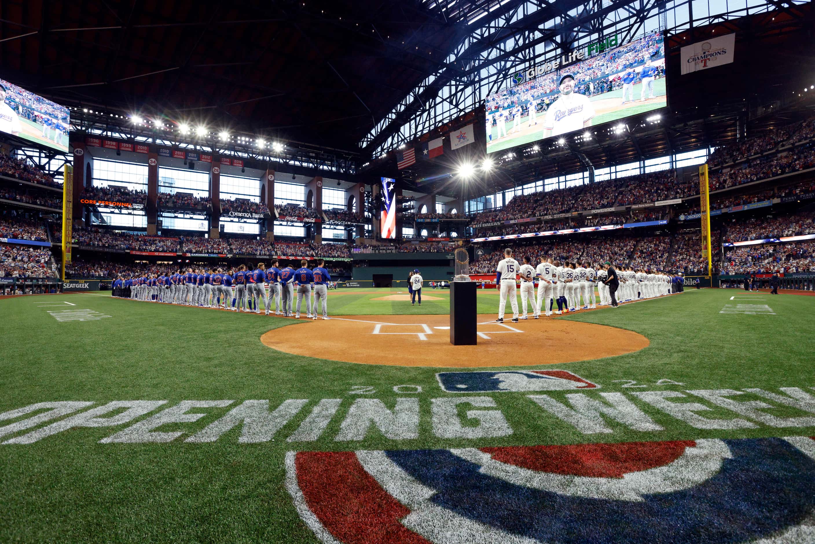 The Texas Rangers stand for the national anthem as the 2023 World Series championship banner...