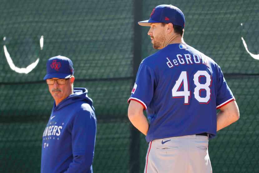 Texas Rangers pitching coach Mike Maddux, left, observes as pitcher Jacob deGrom gets set to...