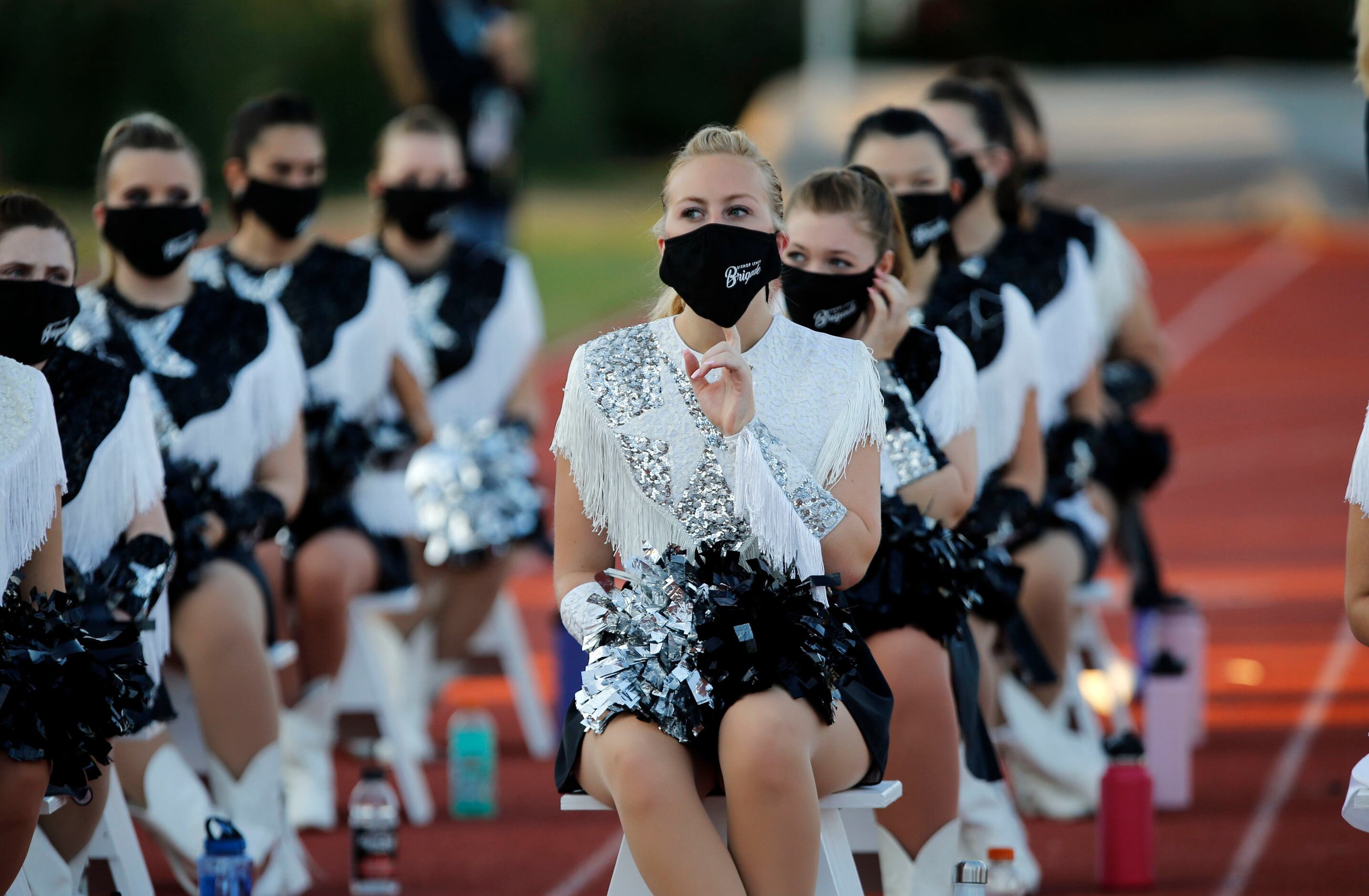The Bishop Lynch drill team takes a breather (clad in masks) before the first half of high...