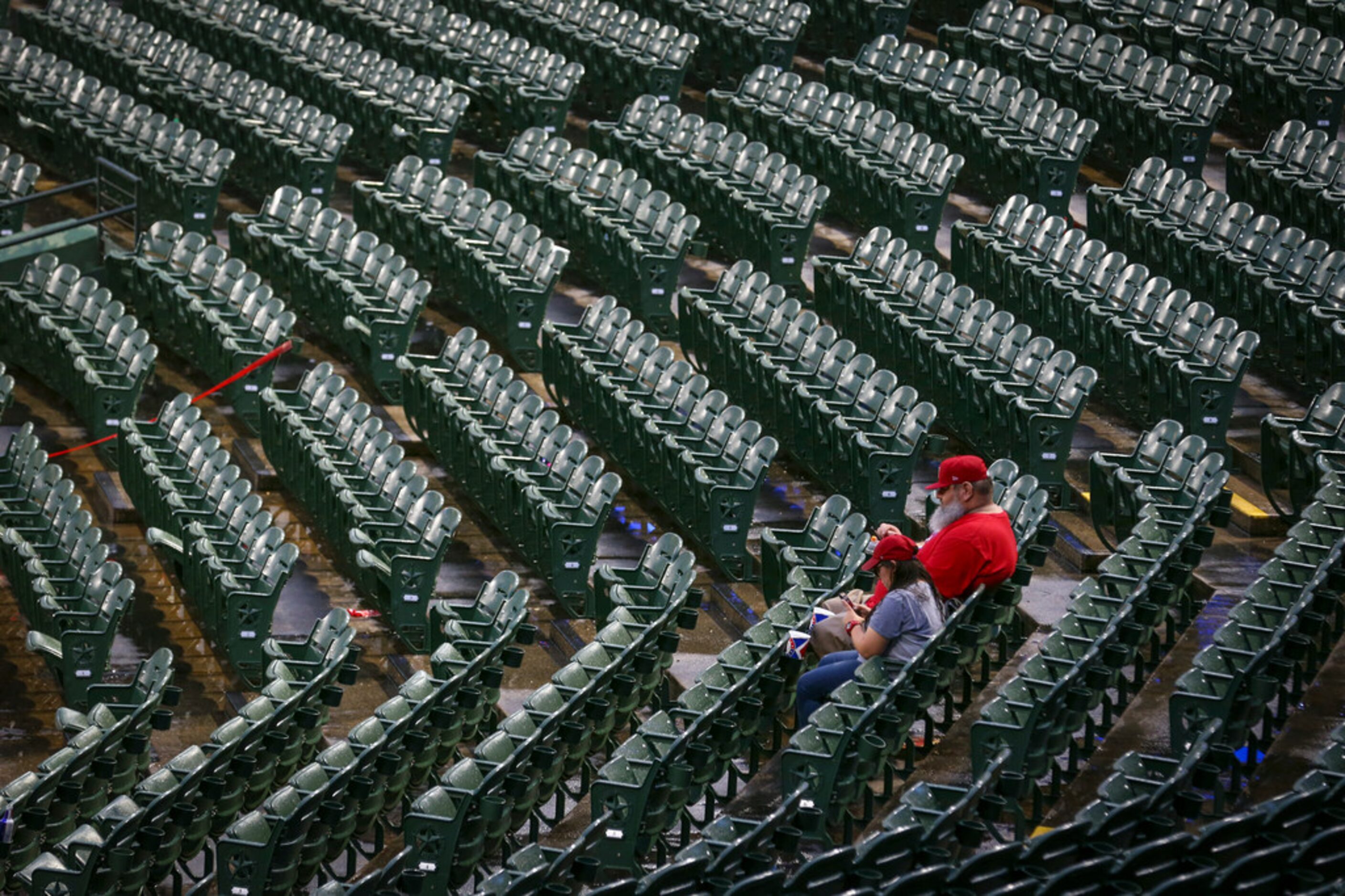 A fan takes a photo of the storm clouds during a rain delay before a baseball game between...