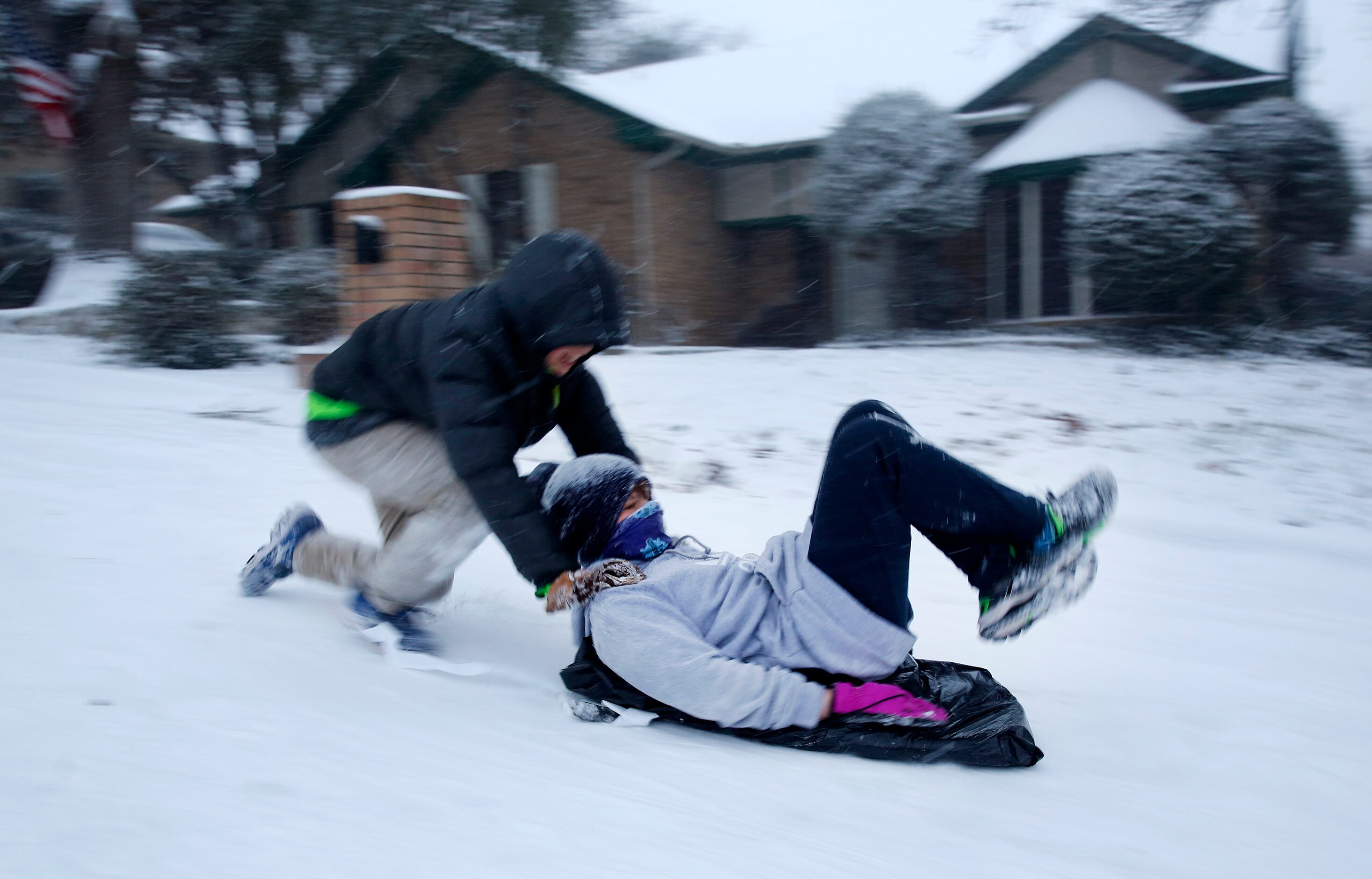 Mitchell Hulme pushes his friend Andew Lim down a steep snow covered street in North...