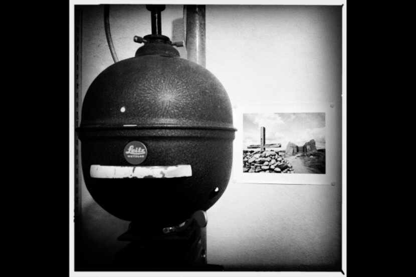 A vintage Leitz enlarger head and an old print tacked to the wall in the printing room.