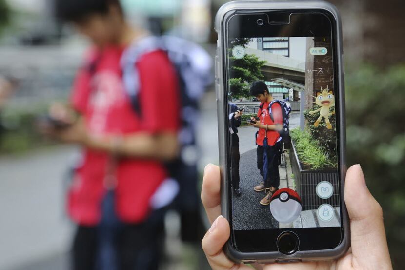FILE - In this July 22, 2016 file photo, Japanese students play "Pokemon Go" in the street...