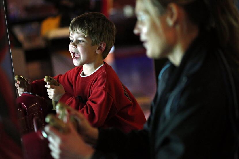 Ben Boyd (left), 5, yells as he plays an arcade game with his mother, Suzette Boyd, at Main...