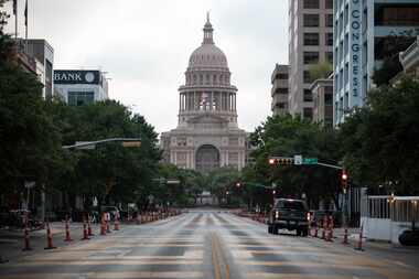 Cars drive on Congress Avenue in front of the Texas Capitol building on July, 14, 2020 in...