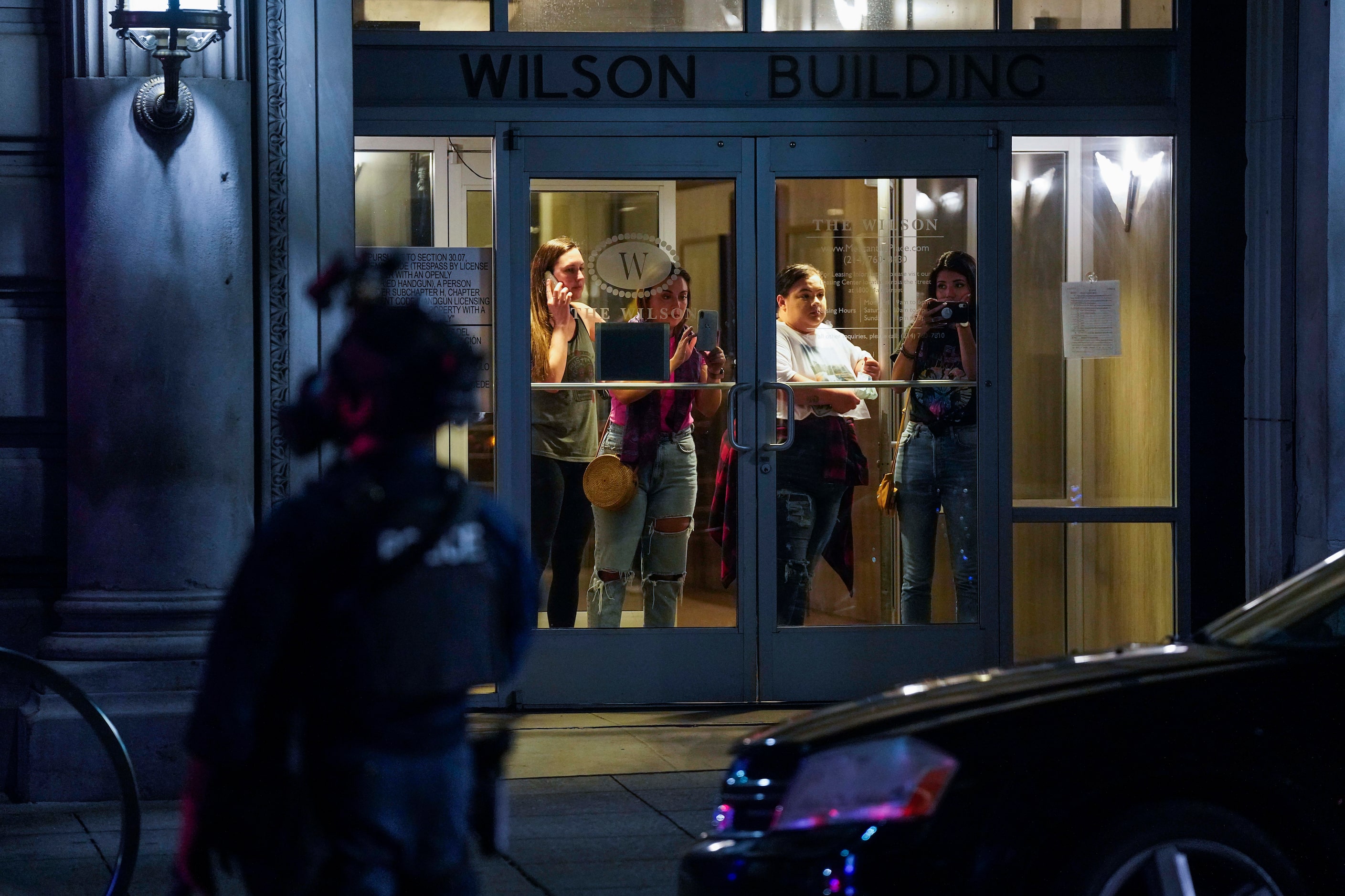 Women watch from the windows of a building on Main Street as Dallas police and  Texas...