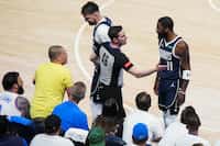 Referee Ben Taylor steps between Dallas Mavericks guard Kyrie Irving (11) and fan Juan...