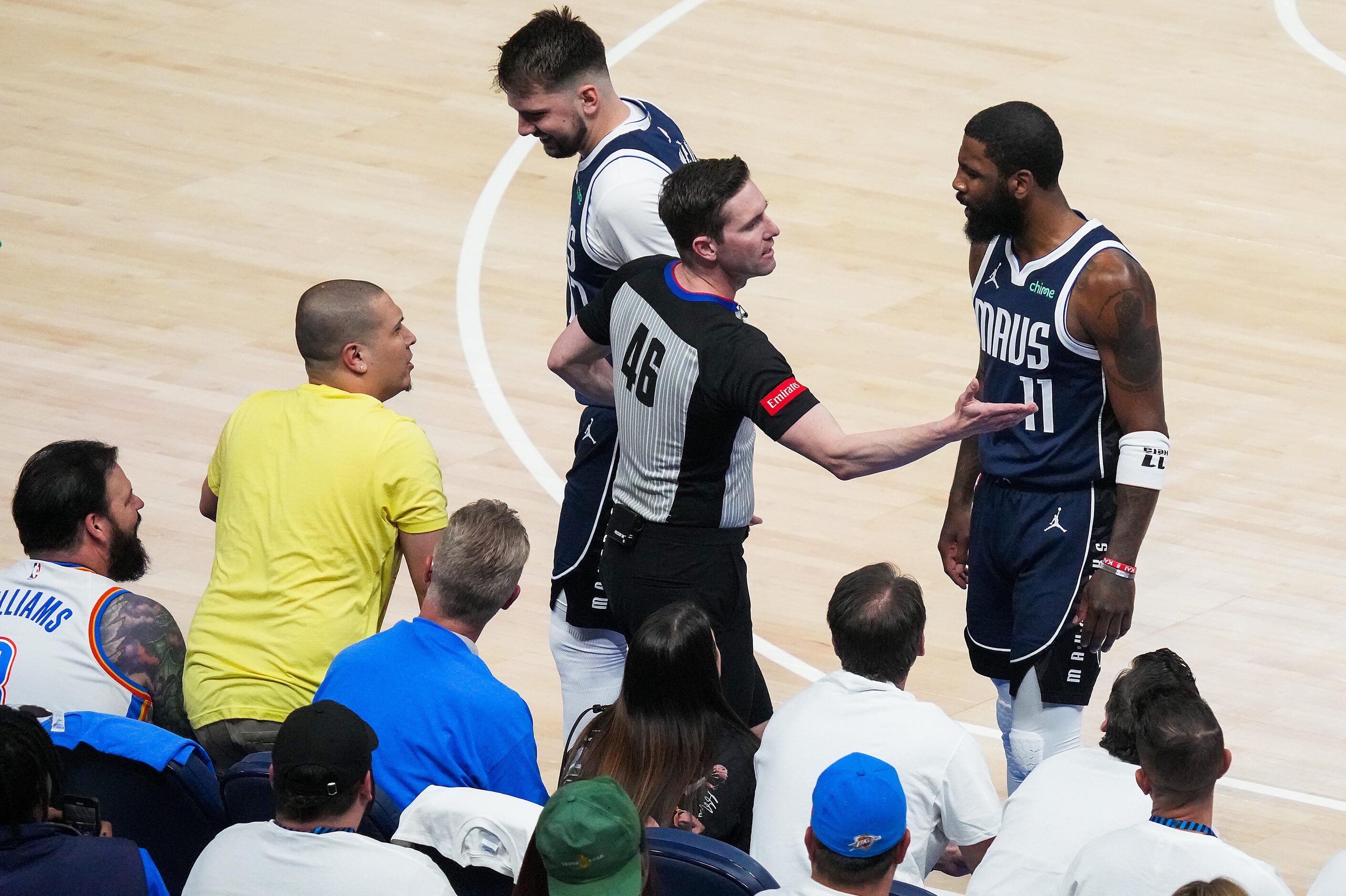 Referee Ben Taylor steps between Dallas Mavericks guard Kyrie Irving (11) and fan Juan...