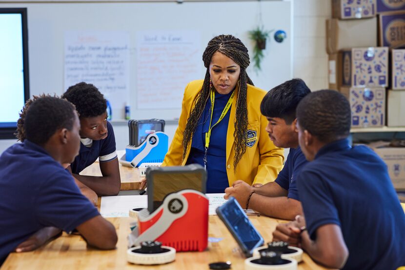 High school students sit at a lab table and work on problem-solving.