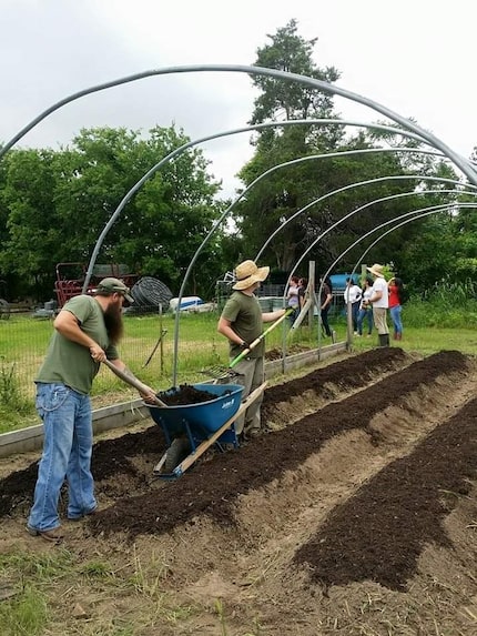 Various people working in a field, setting up rows for planting seeds and creating a...