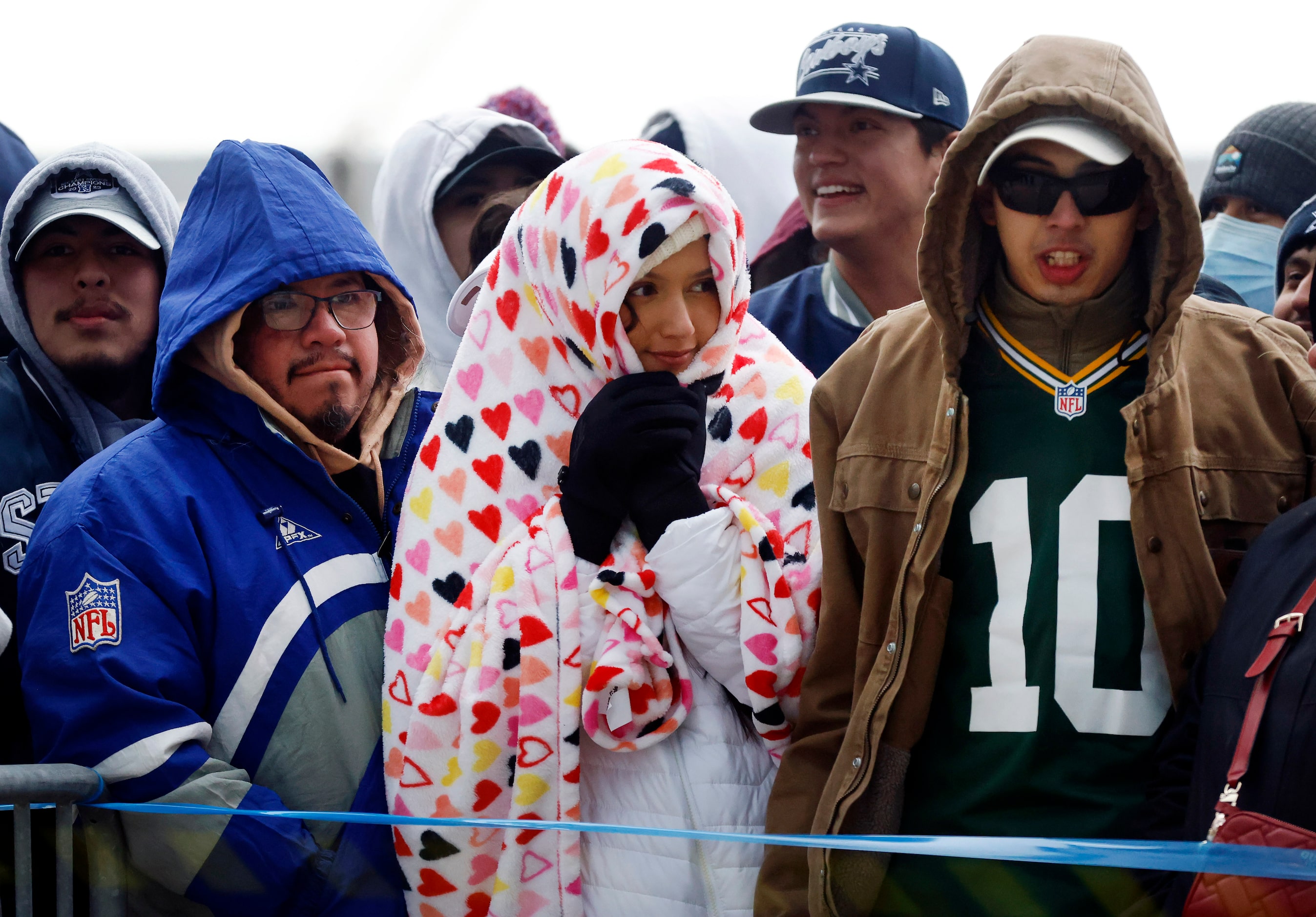 Dallas Cowboys and Green Bay Packers fans keep warm on the west plaza as they wait to get...