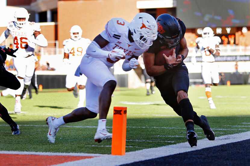 Quarterback Spencer Sanders #3 of the Oklahoma State Cowboys gets hit out of bounds by...