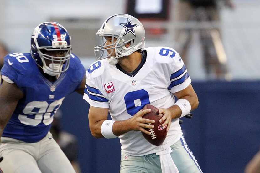 Dallas Cowboys quarterback Tony Romo (9) scrambles away from New York Giants defensive end...