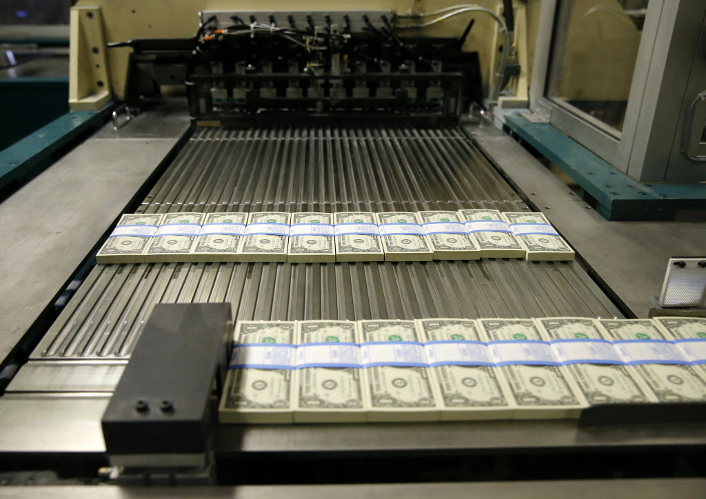 Newly printed $1 bills move along the production line at the Bureau of Engraving and...