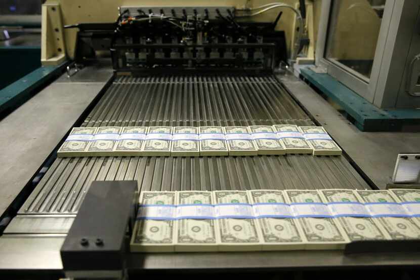 Newly printed $1 bills move along the production line at the Bureau of Engraving and...