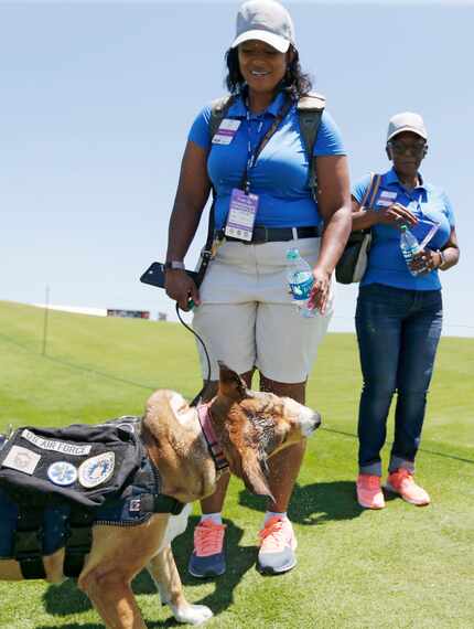 Air Force veteran LaWanna Viers gives her service dog Corey some water near the green of...