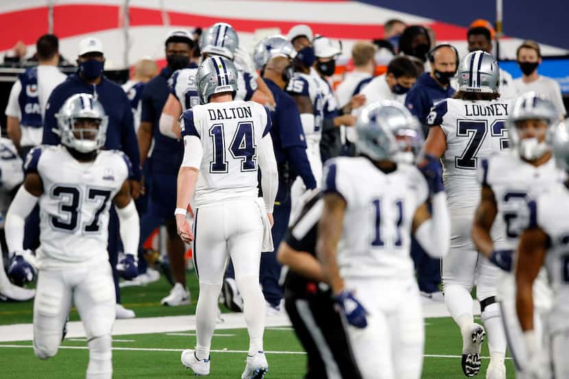 Cowboys quarterback Andy Dalton (14) walks to the sideline after throwing an interception in...