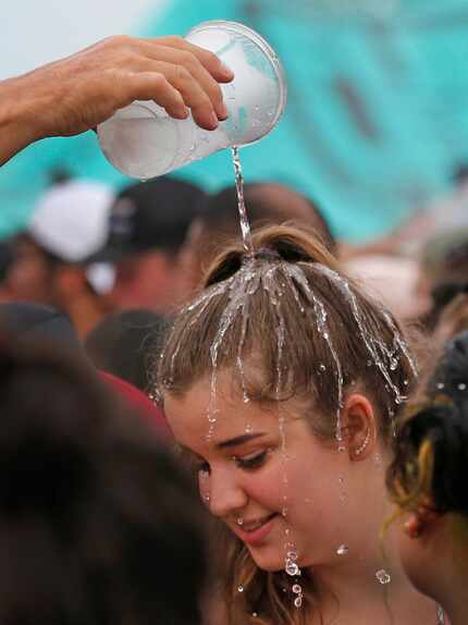 A concert goer cools off with a cup of cold water at the Warped Tour in Dallas.