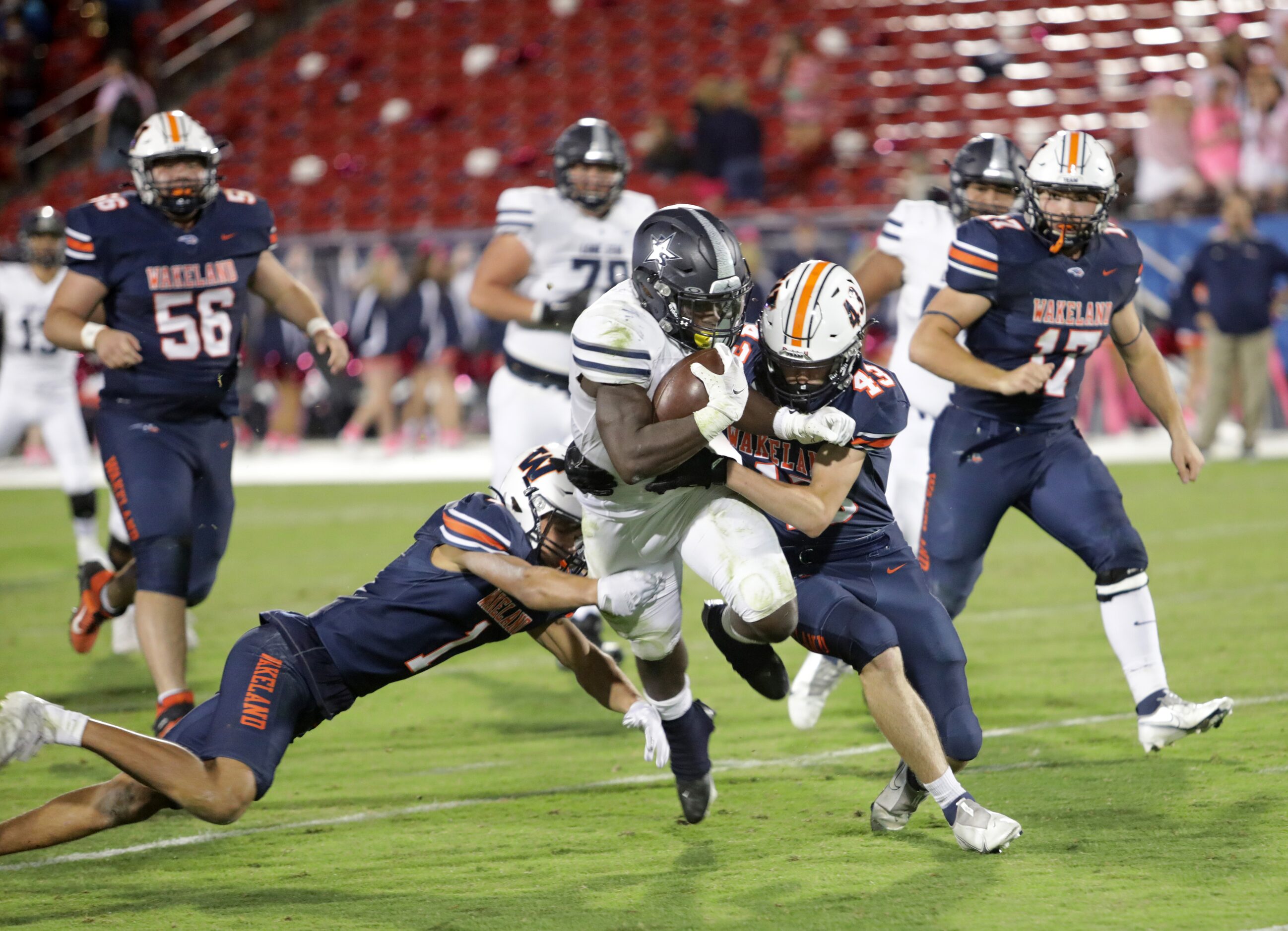 Lone Star player #2, Ashton Jeanty, is brought down by Wakeland players #1, Davion Woolen,...