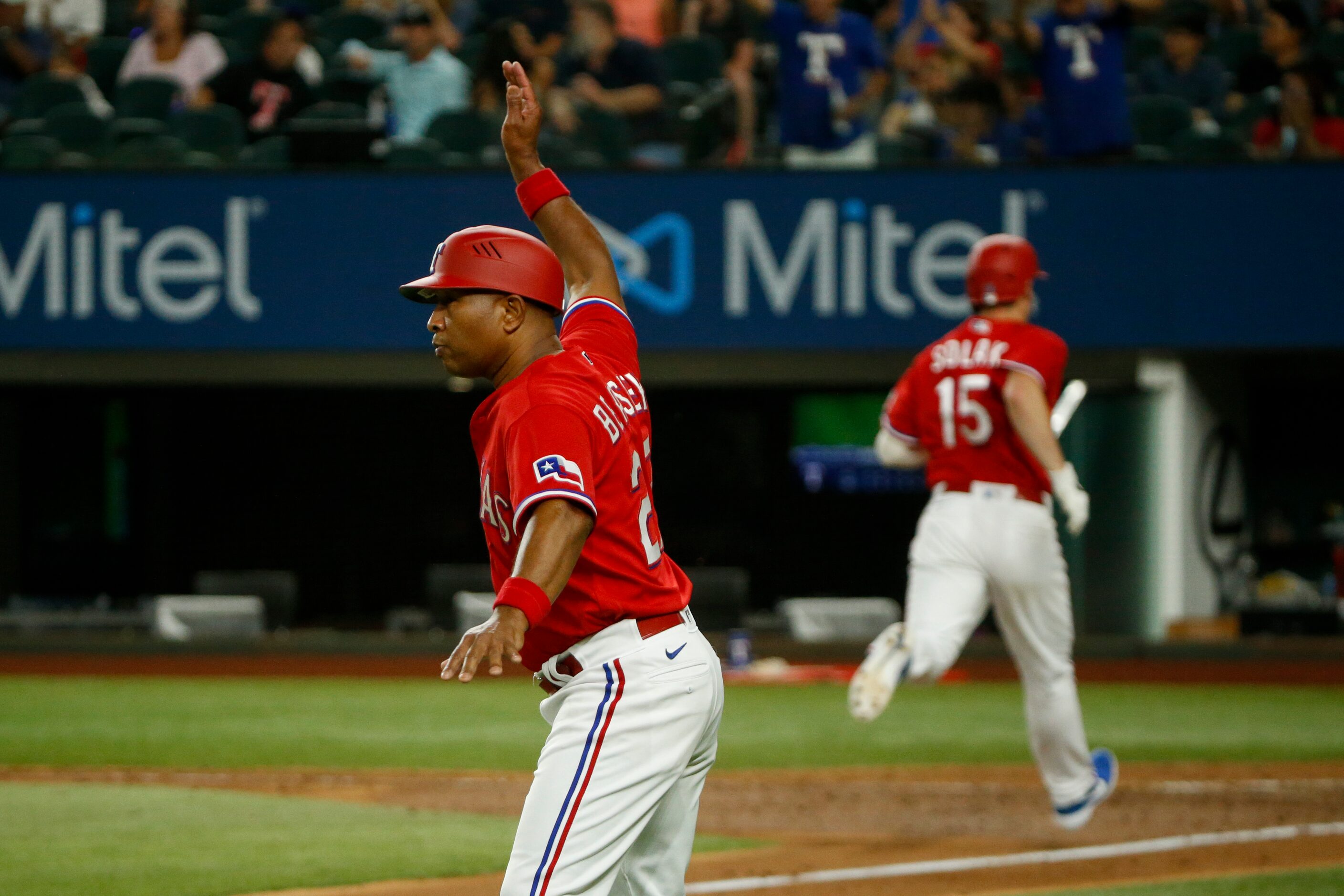 Texas Rangers third base coach Tony Beasley (27) waves the runners around to score during...