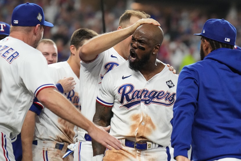 Texas Rangers' Adolis Garcia is mobbed at home plate after hitting a walk-off home run...