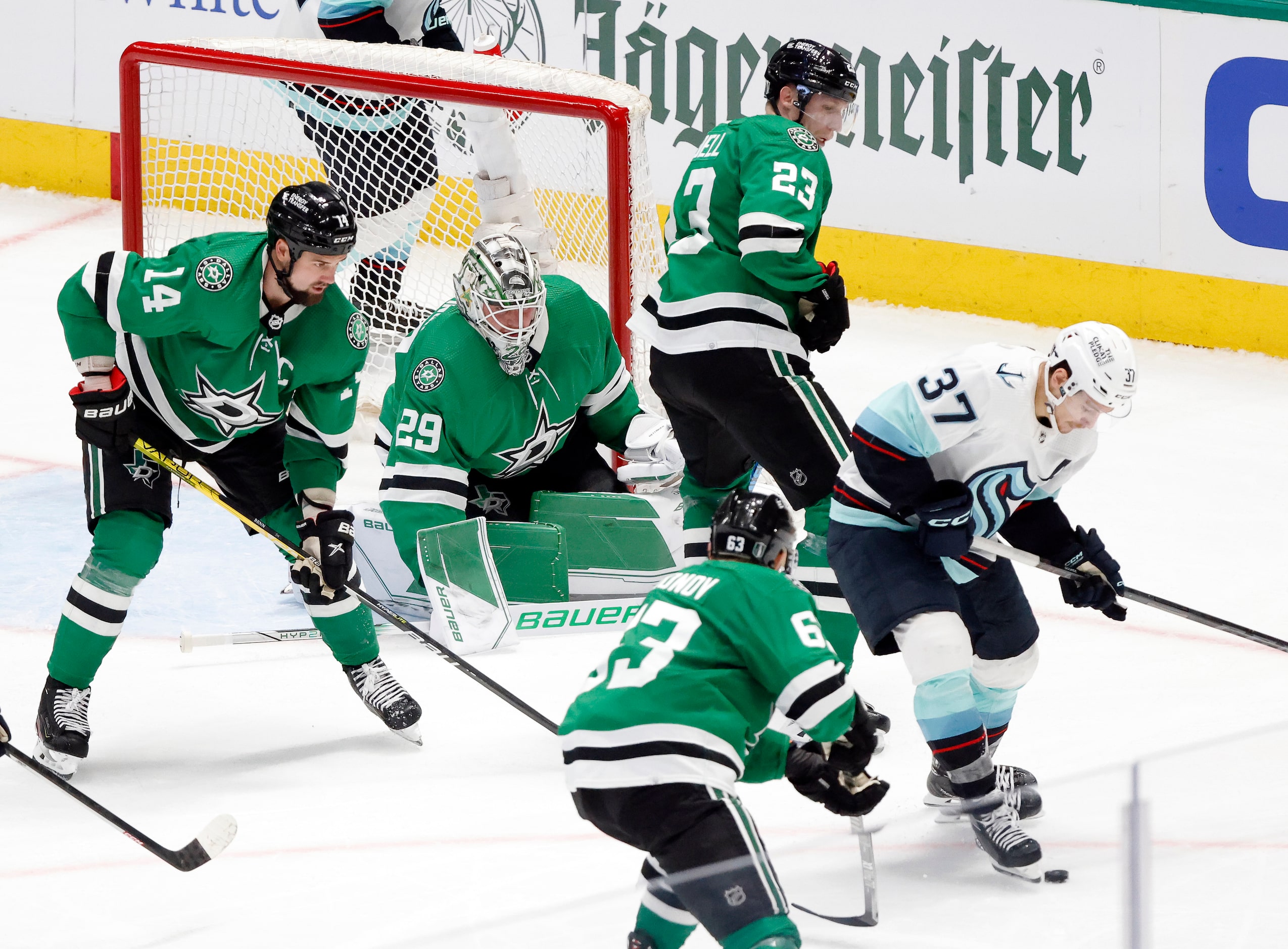 The Dallas Stars defense surrounds goaltender Jake Oettinger (29) as the Seattle Kraken...