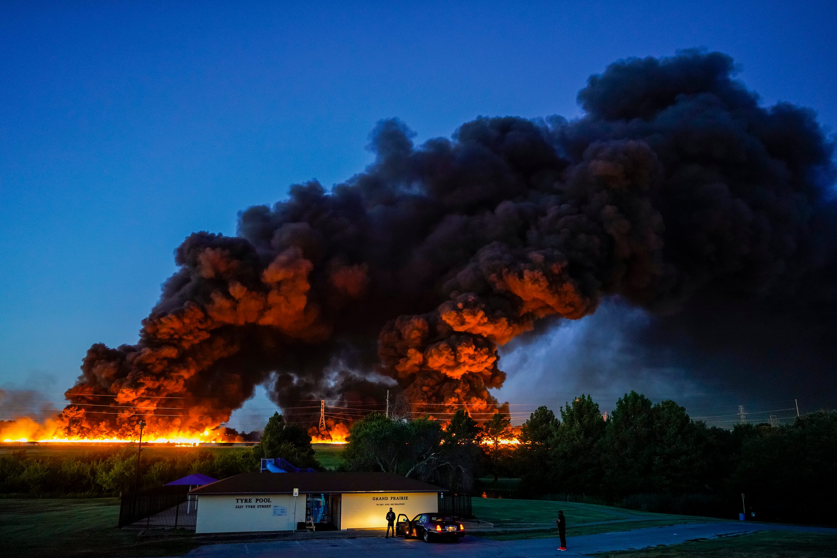 A plume of smoke rises over people gathered in Tyre Park to watch fire crews battle a...