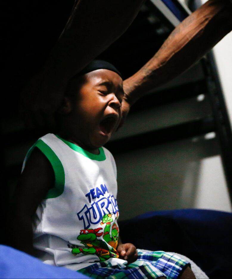 Jordan Miller, 2, yawns while his dad finishes getting him ready for the day at The Family...