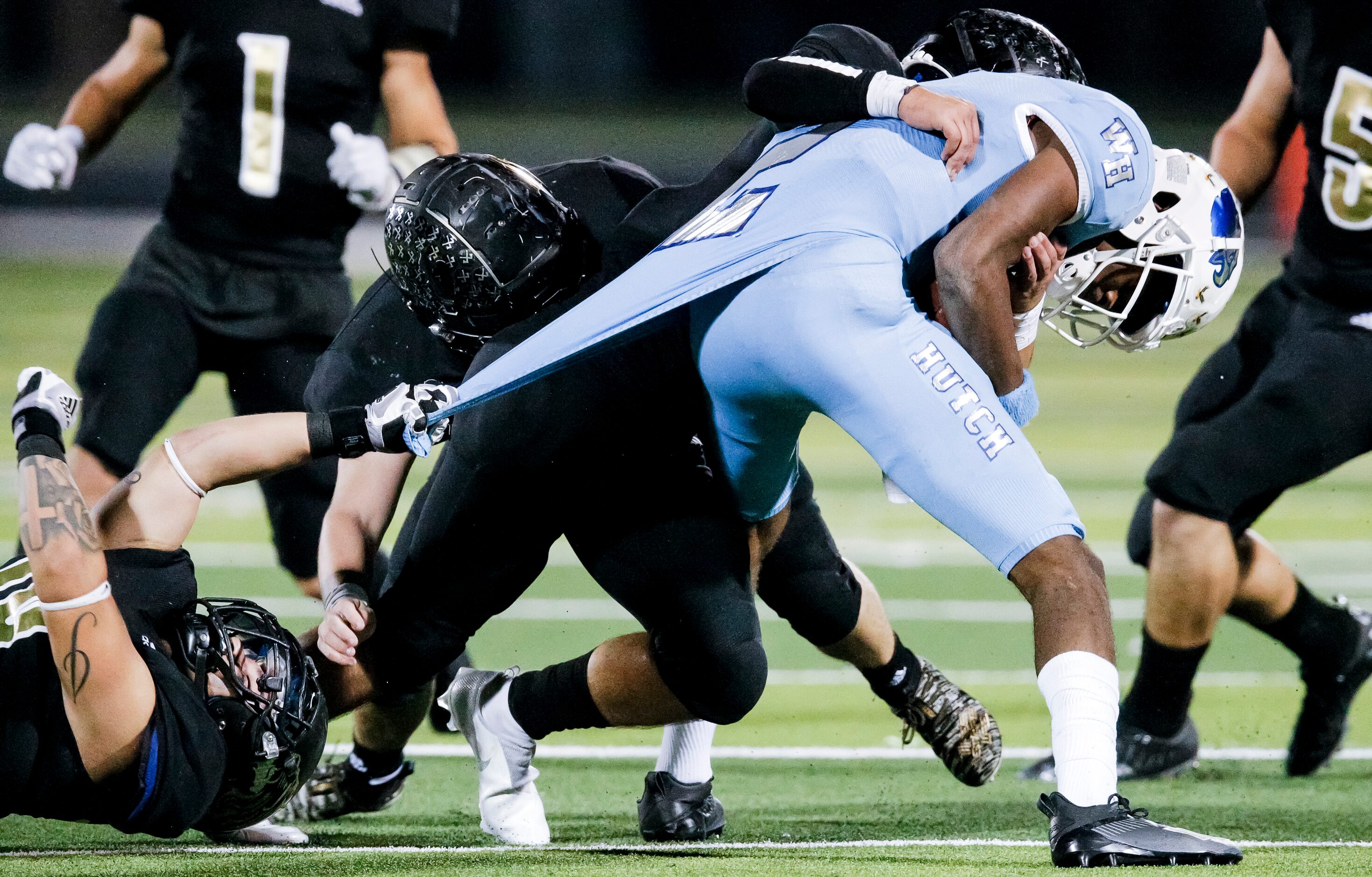 Wilmer-Hutchins senior quarterback Andre Henderson (2) is tackled by Kaufman defenders...