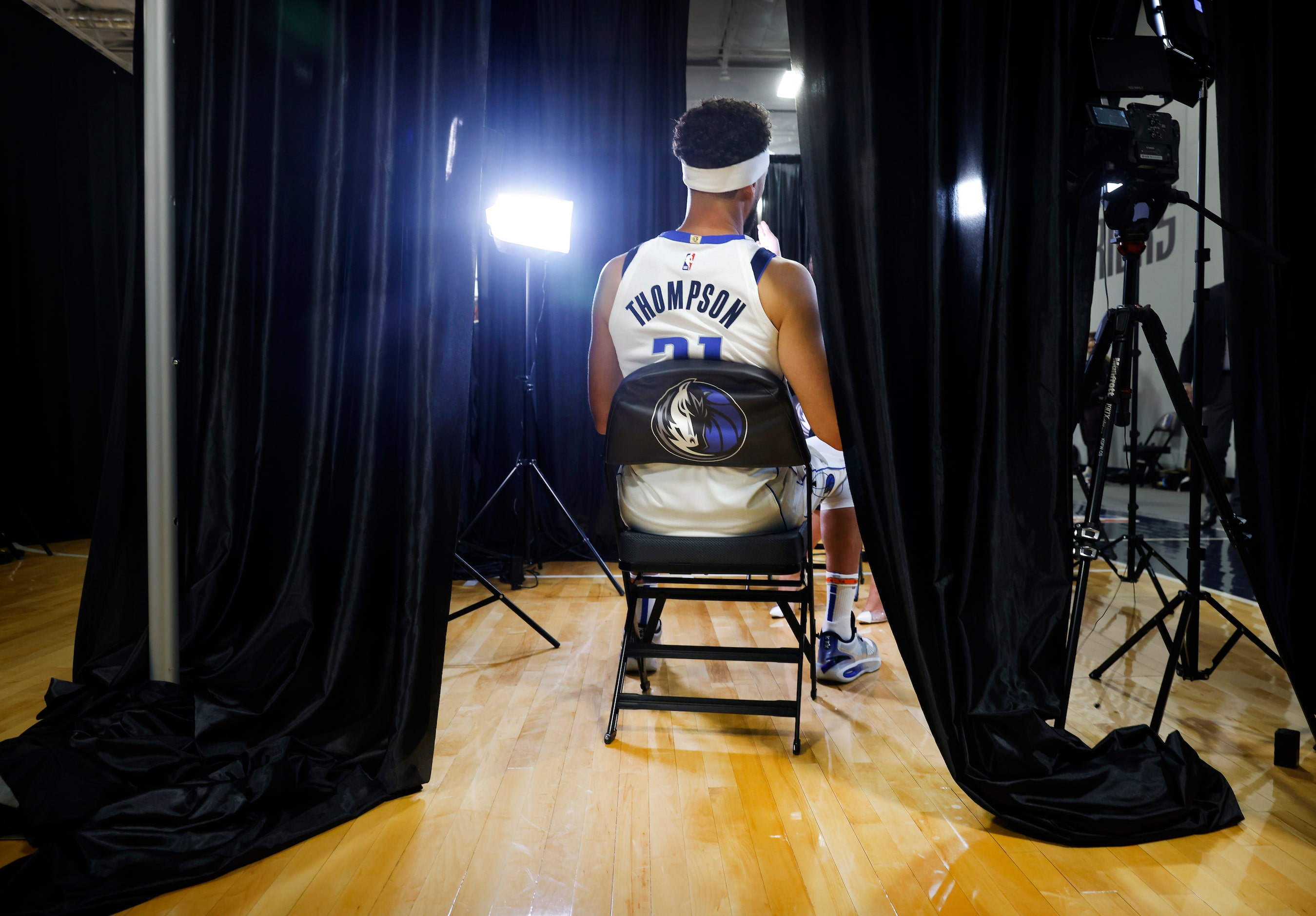 Dallas Mavericks forward Klay Thompson sits in a black curtained booth for a television...