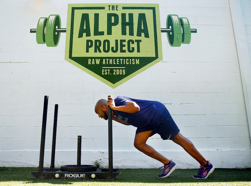 Donovan Lewis pushes a weighted sled across the turf during his workout behind the Alpha...