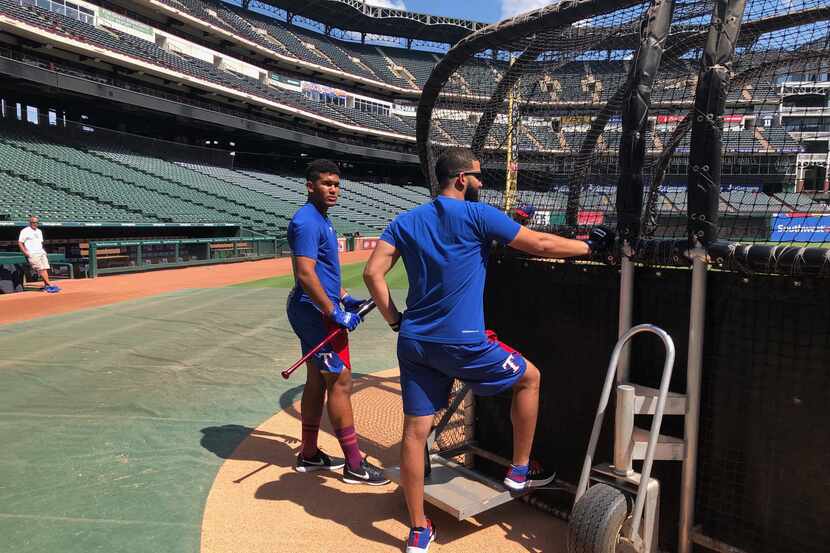 New Rangers prospect Bayron Lora, left, took batting practice with the Rangers on Wednesday....
