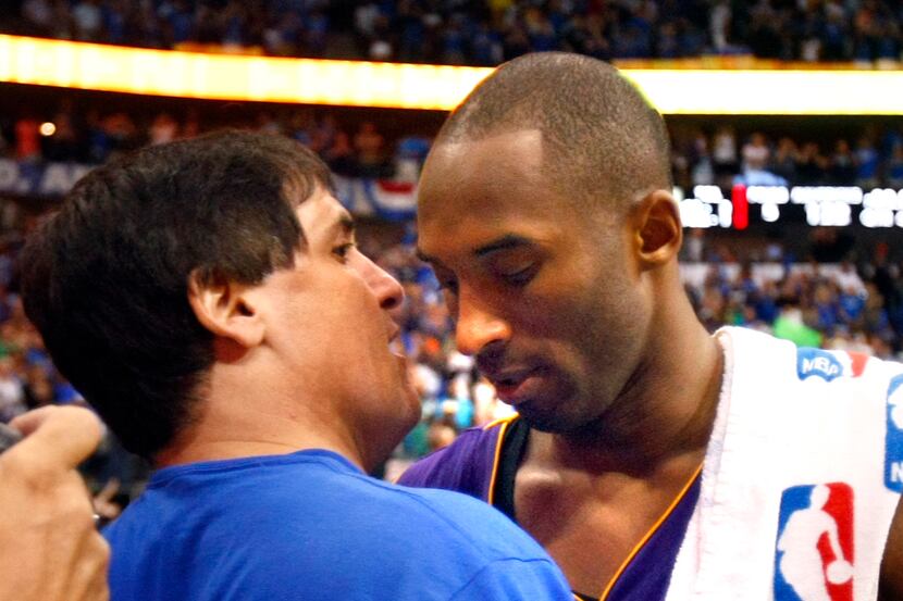 Dallas Mavericks owner Mark Cuban, left, hugs Los Angeles Lakers shooting guard Kobe Bryant...