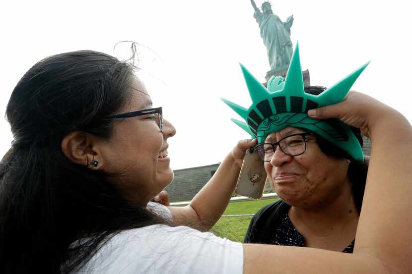 Karen Mejia (left) fits her mother, Leonor Chipayo, with a souvenir Statue of Liberty foam...