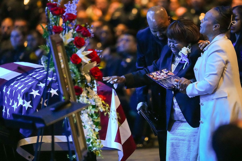 Cherie Jeffery is supported by family members as she reaches out to touch the casket during...