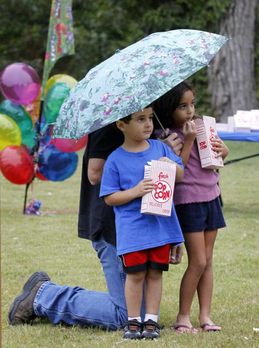 Rick Peters holds an umbrella for his son, Luke Peters, 4, and daughter Alexa Peters, 6,...