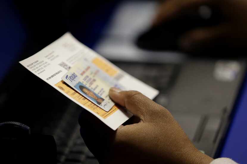 An election official checks a voter's photo identification in Austin.