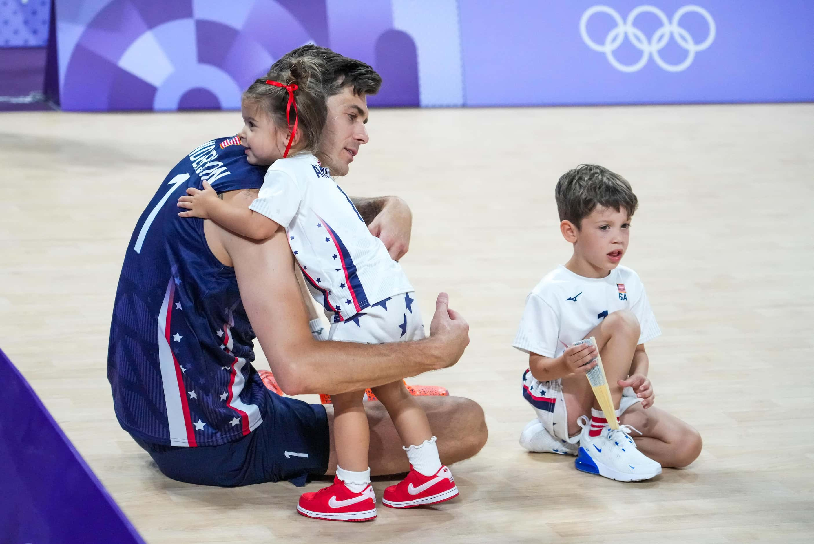 Matthew Anderson of the United States sits on the court with his children after a loss to...