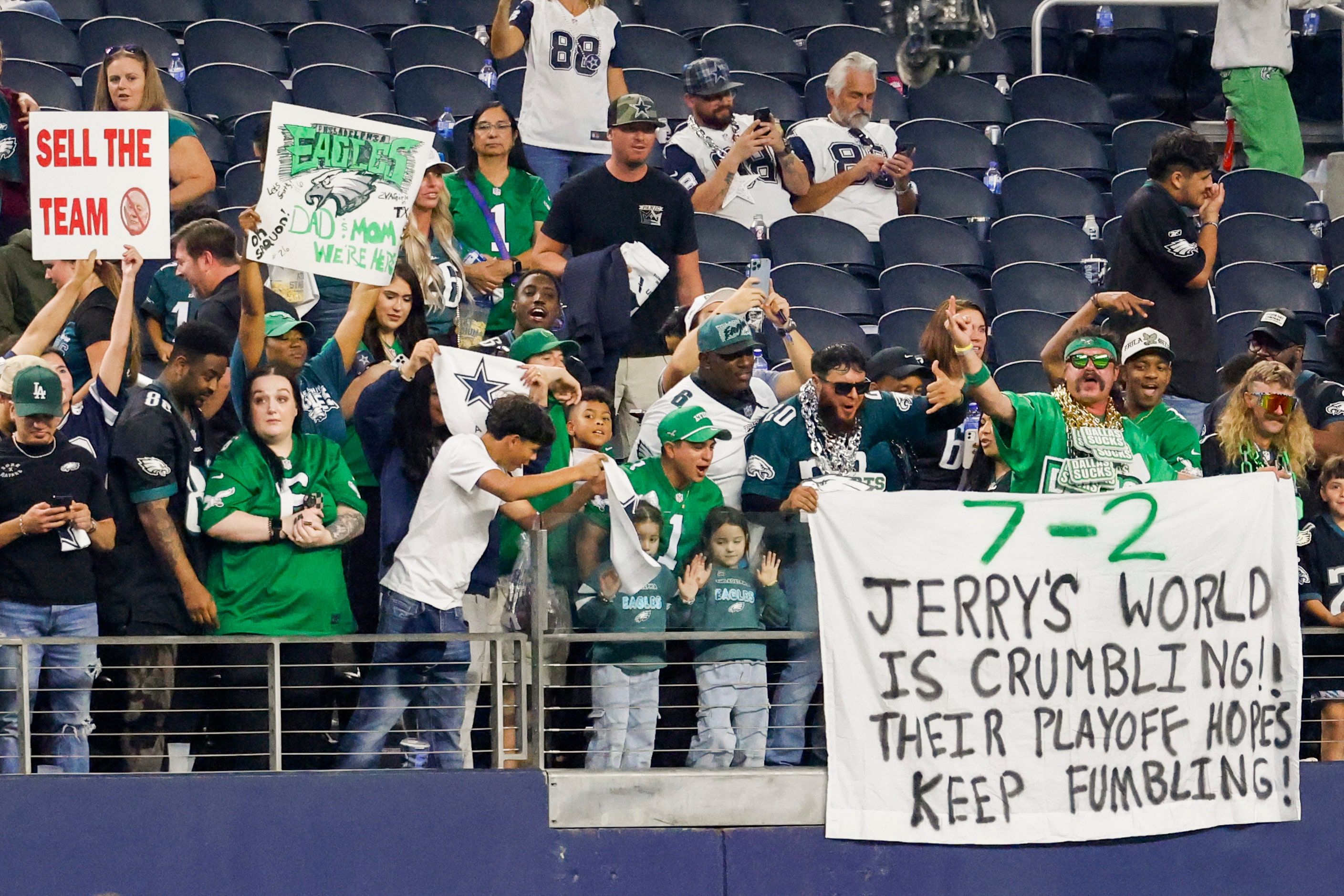 Philadelphia Eagles fans hold a banner as Dallas Cowboys fans hold a sign saying “sell the...