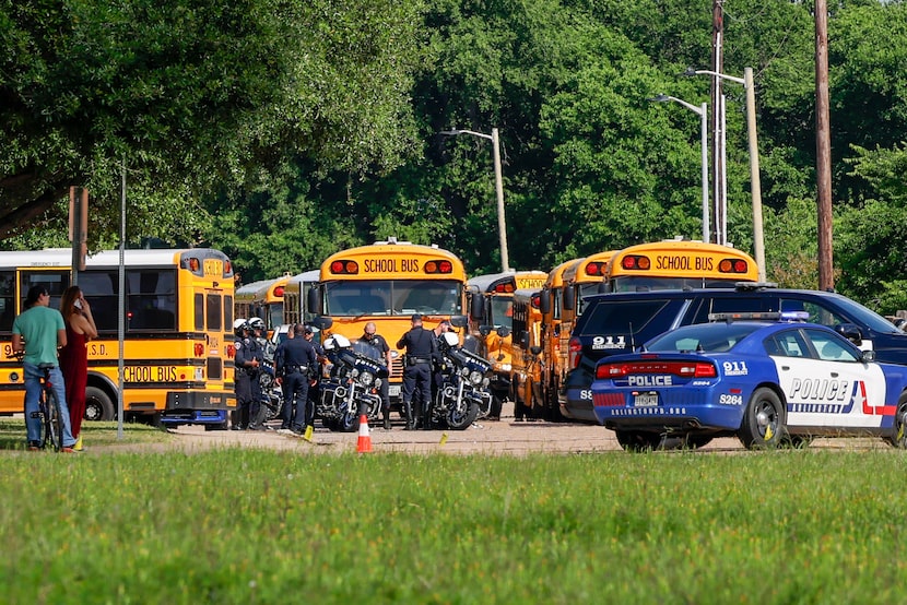 Several police motorcycles sit in front of several school buses after a shooting occurred...